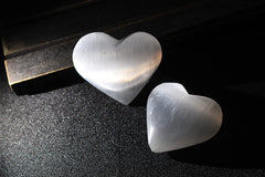 AMOYSTONE selenite heart used as a palm massage stone for stress relief.