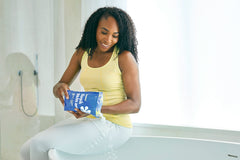 ASUTRA bath flakes poured into warm water for a soothing soak.