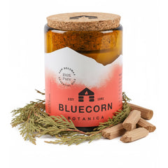 Bluecorn Beeswax candle in amber glass holder enhances warm ambience.