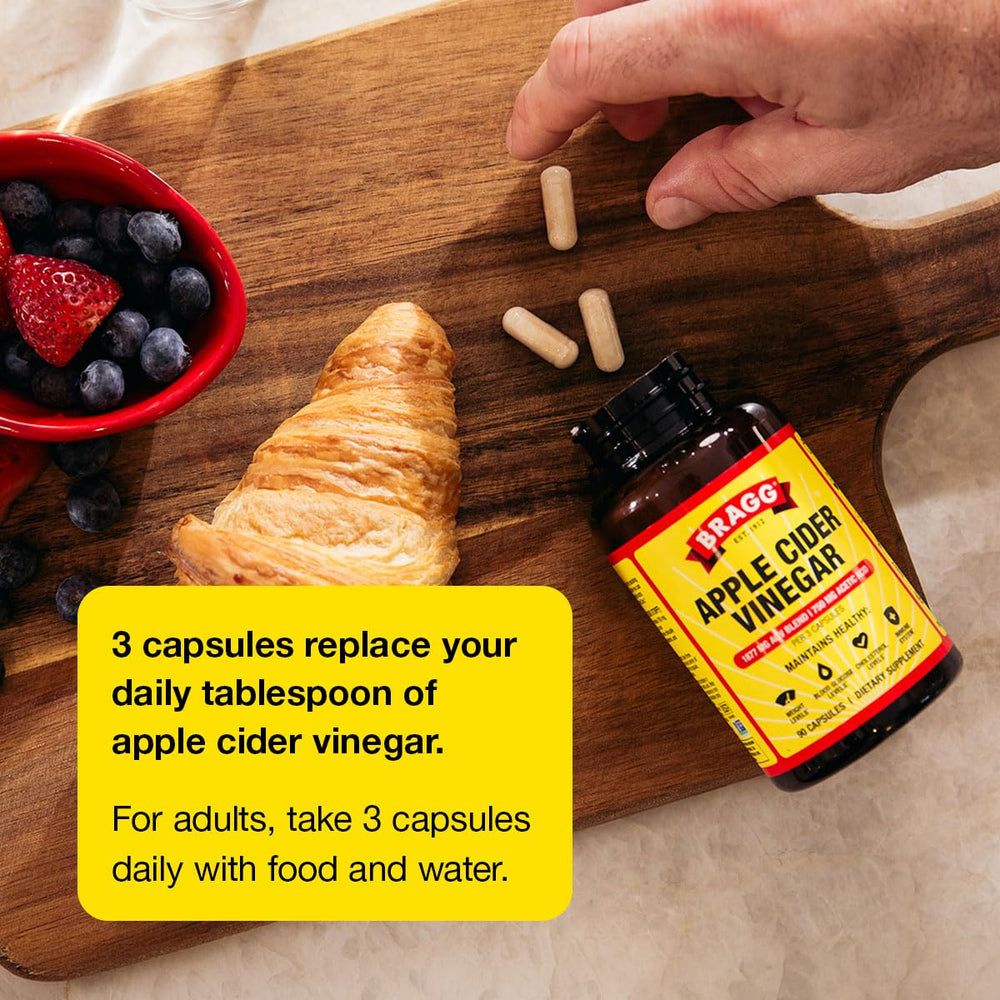 Bragg ACV capsules beside water for easy intake.