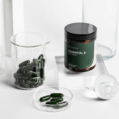 Eimele Essential 8 bottle on wood surface indicating vegan, non-GMO formula.