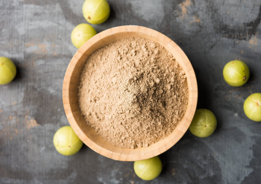 Amla powder being poured into a smoothie for a tangy boost.