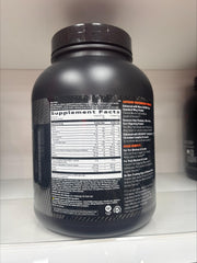 GNC AMP Wheybolic coconut caramel powder pouring into a shaker