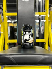 NutraBio Classic Whey powder being poured into a shaker.