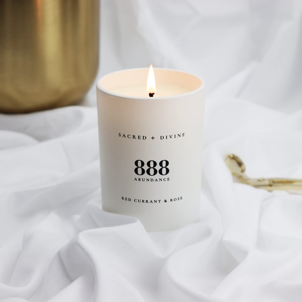 Sacred + Divine 888 abundance candle warm flame creates calming atmosphere.