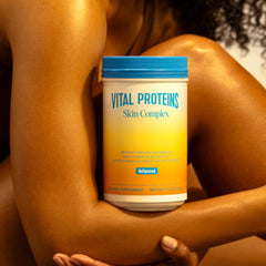 Vital Proteins Skin Complex beside glass of water for daily practice.