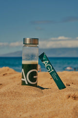 AG1 bottle with glass demonstrates ready-to-use daily nutrition.