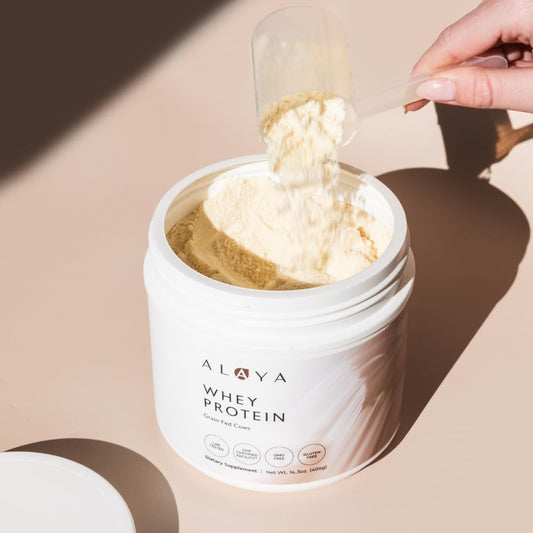 Alaya Naturals vanilla whey powder scoop beside the tub for clean nutrition.