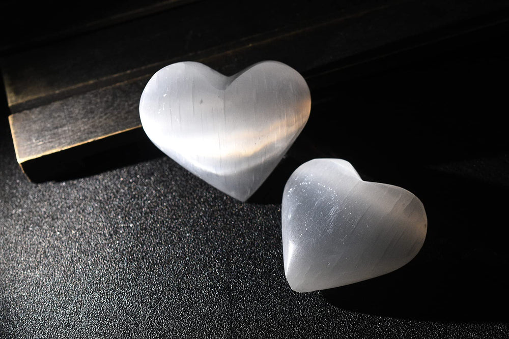AMOYSTONE selenite heart used as a palm massage stone for stress relief.