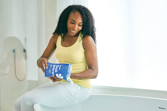 ASUTRA bath flakes poured into warm water for a soothing soak.