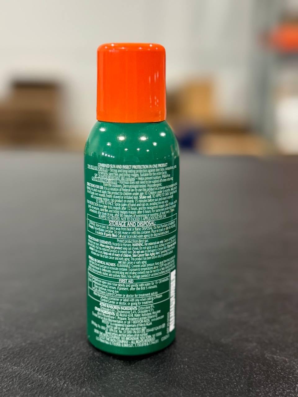 Hands applying AVON Bug Guard Expedition spray during a hike to repel pests.