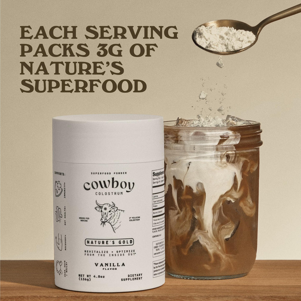 Cowboy Colostrum Powder in a glass with scoop, ready to blend into coffee or smoothies.
