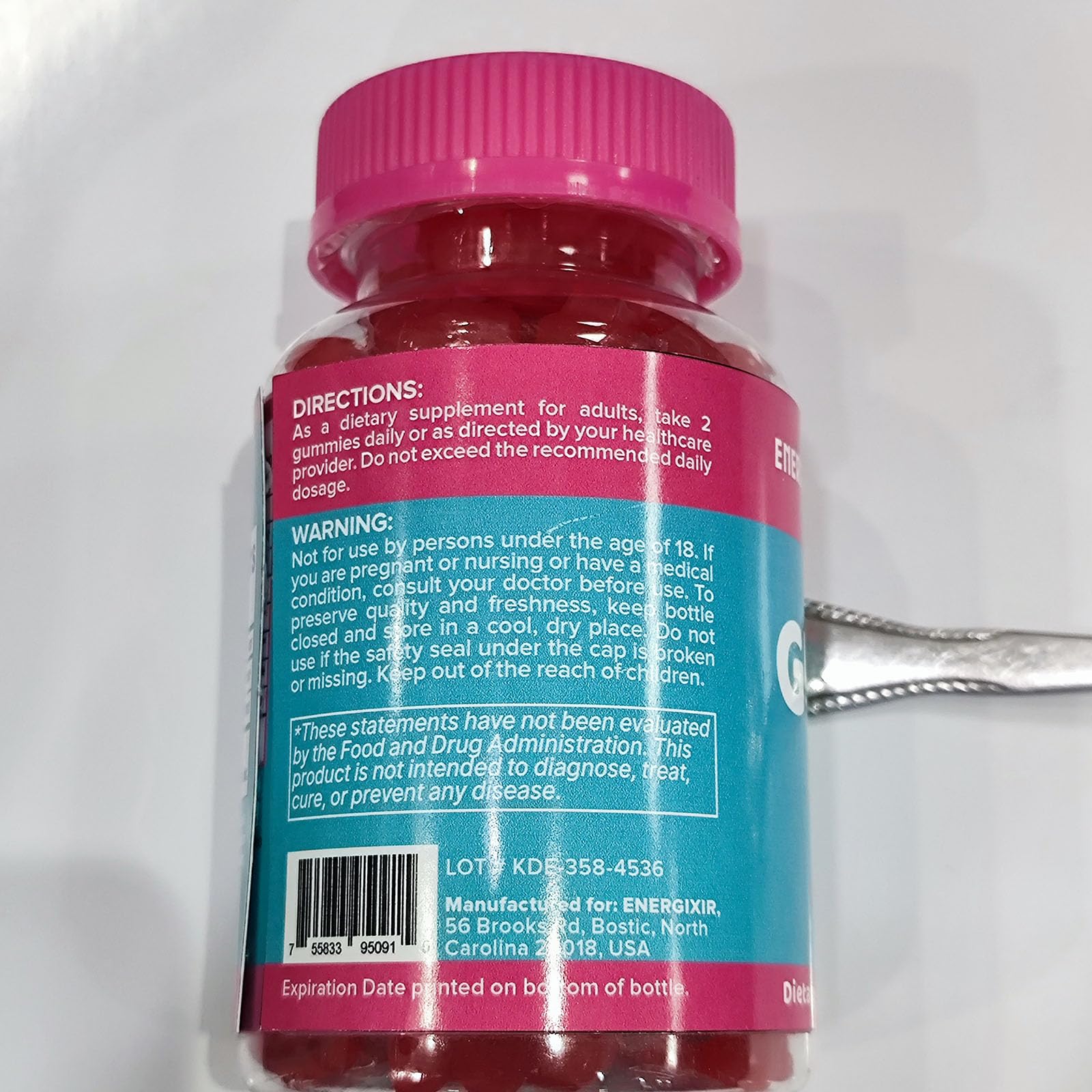 Serving two gummies beside a measuring spoon for portion clarity.
