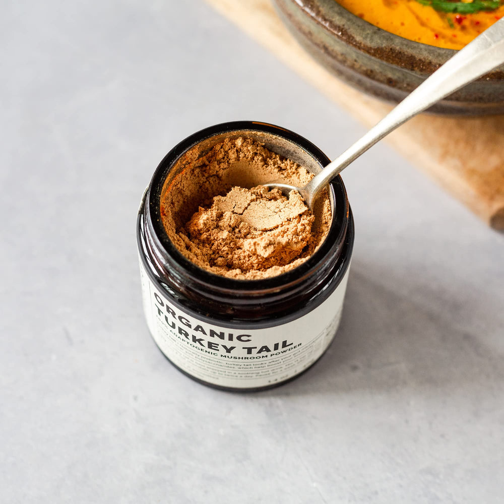 Pouring Erbology Turkey Tail powder into a hot beverage for easy mixing