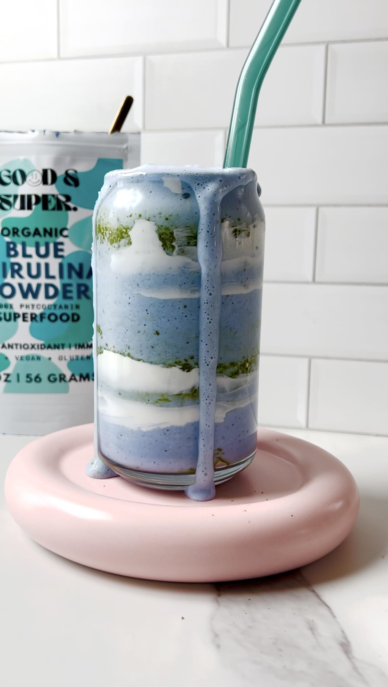 Pure water-extracted spirulina powder displayed beside jar on counter.