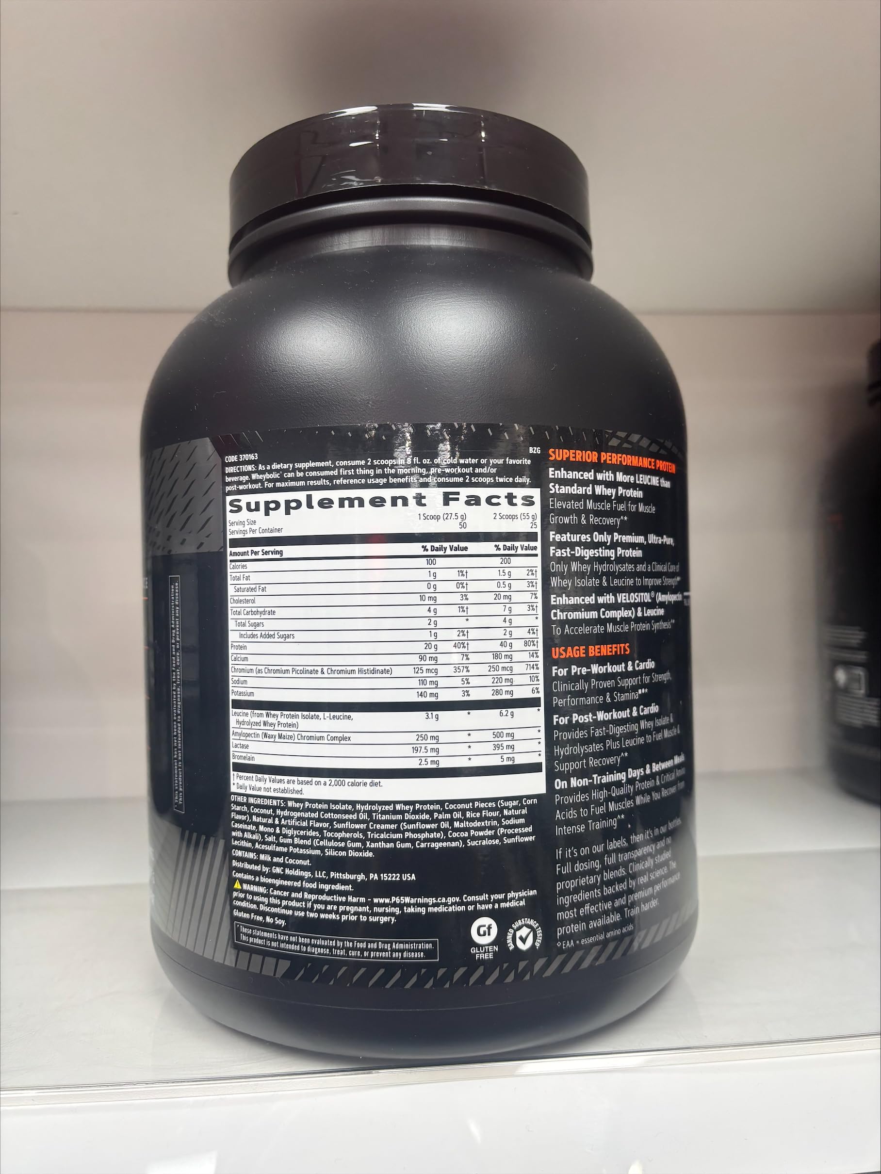 GNC AMP Wheybolic coconut caramel powder pouring into a shaker