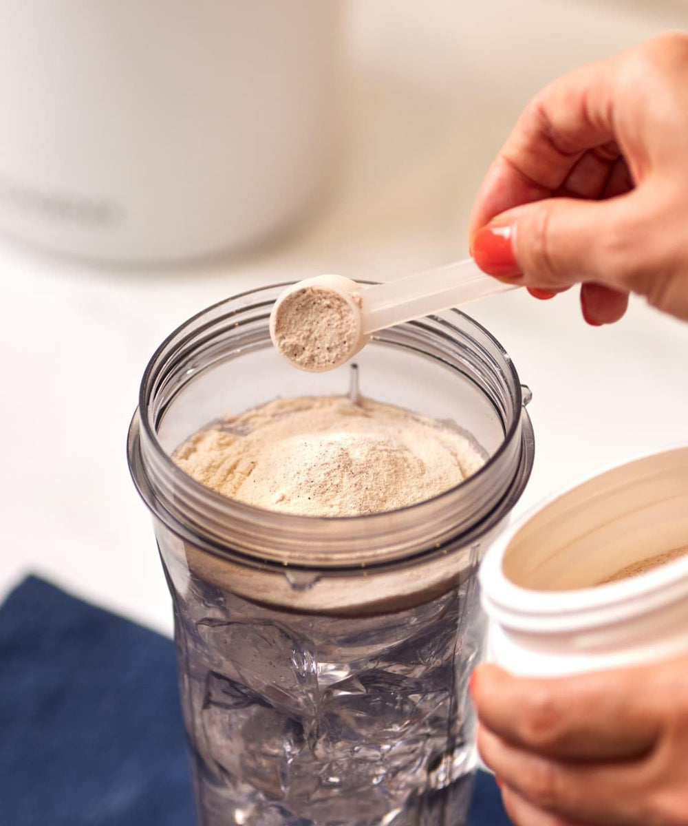 Isagenix Heart Shake Booster container on a kitchen counter, vegan and clean ingredients.