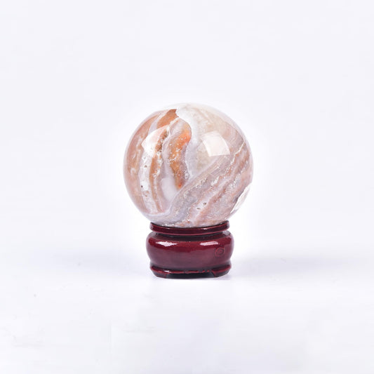 JIC Gem pink agate sphere on a wooden stand for display and energy balance.