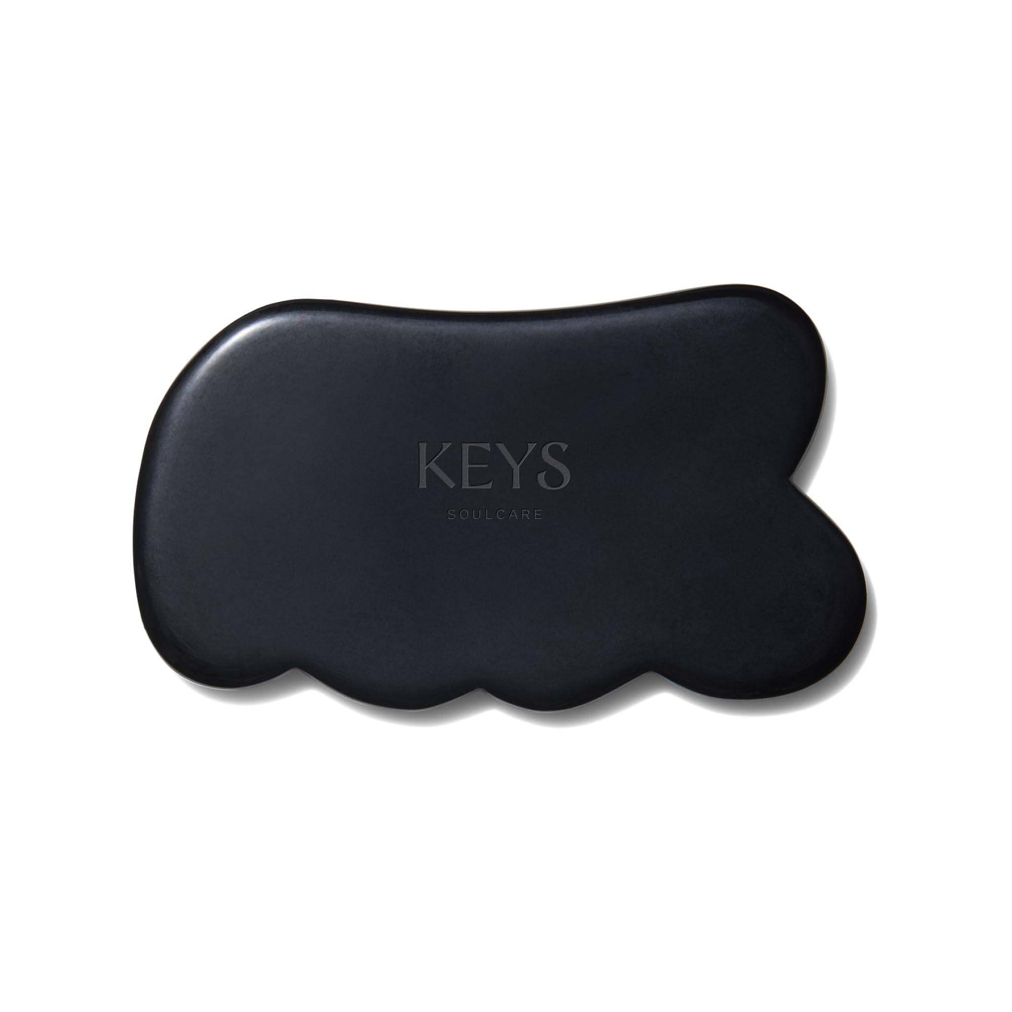 Keys Soulcare obsidian gua sha tool held for body massage and energy balance.