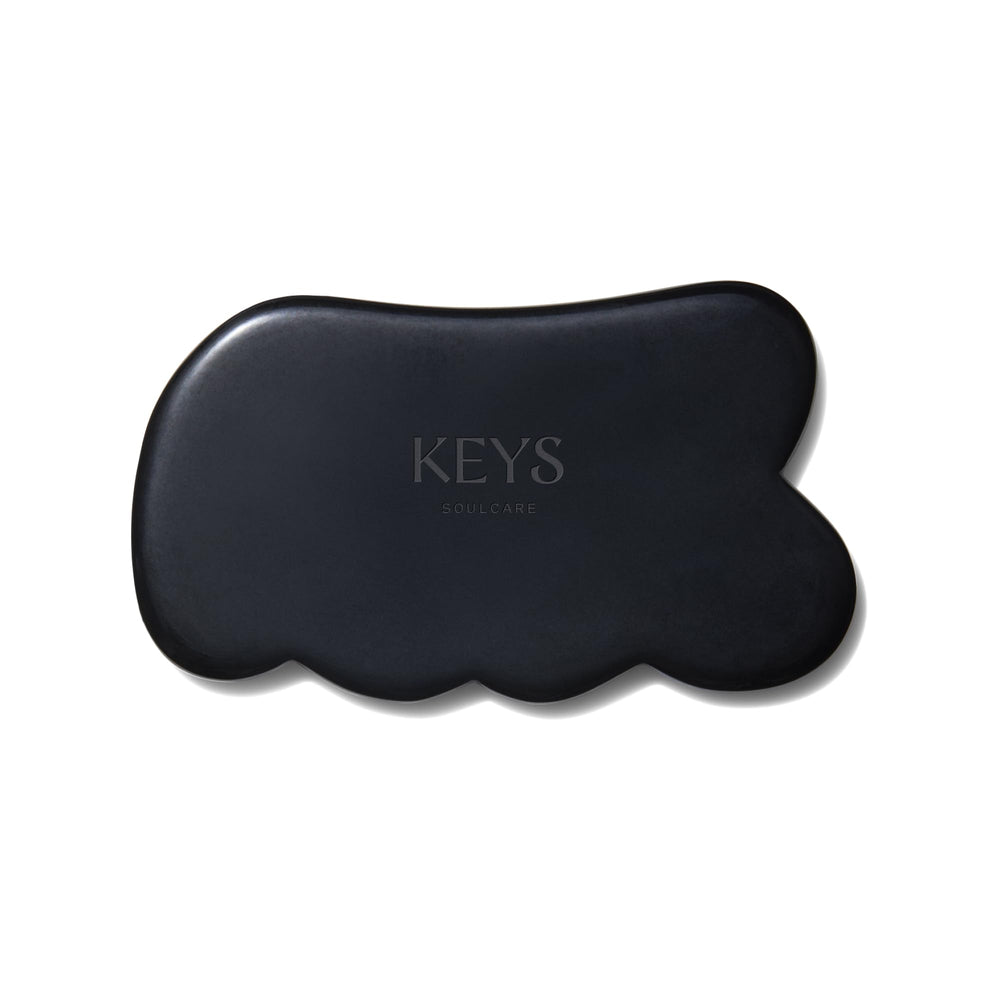 Keys Soulcare obsidian gua sha tool held for body massage and energy balance.