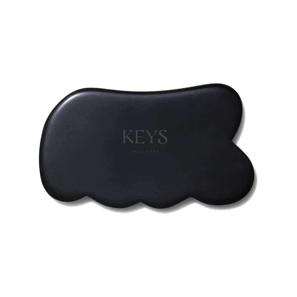 Keys Soulcare obsidian gua sha tool held for body massage and energy balance.