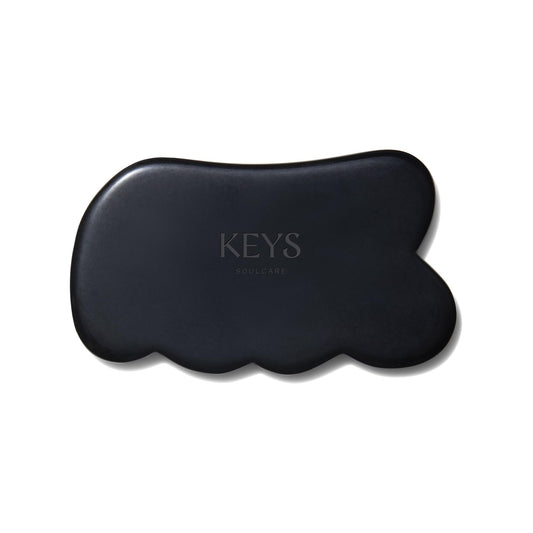 Keys Soulcare obsidian gua sha tool held for body massage and energy balance.