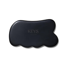 Keys Soulcare obsidian gua sha tool held for body massage and energy balance.