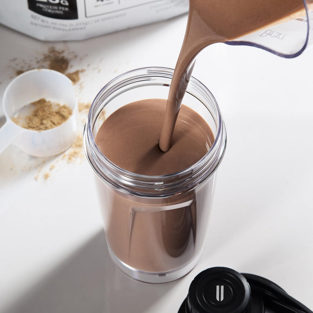 NOBULL protein shake in glass shows smooth texture for recovery after workouts.