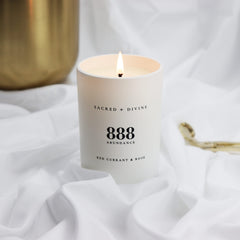Sacred + Divine 888 abundance candle warm flame creates calming atmosphere.