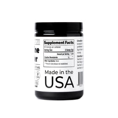 Santa Cruz Paleo creatine powder on a kitchen counter beside a protein shake.