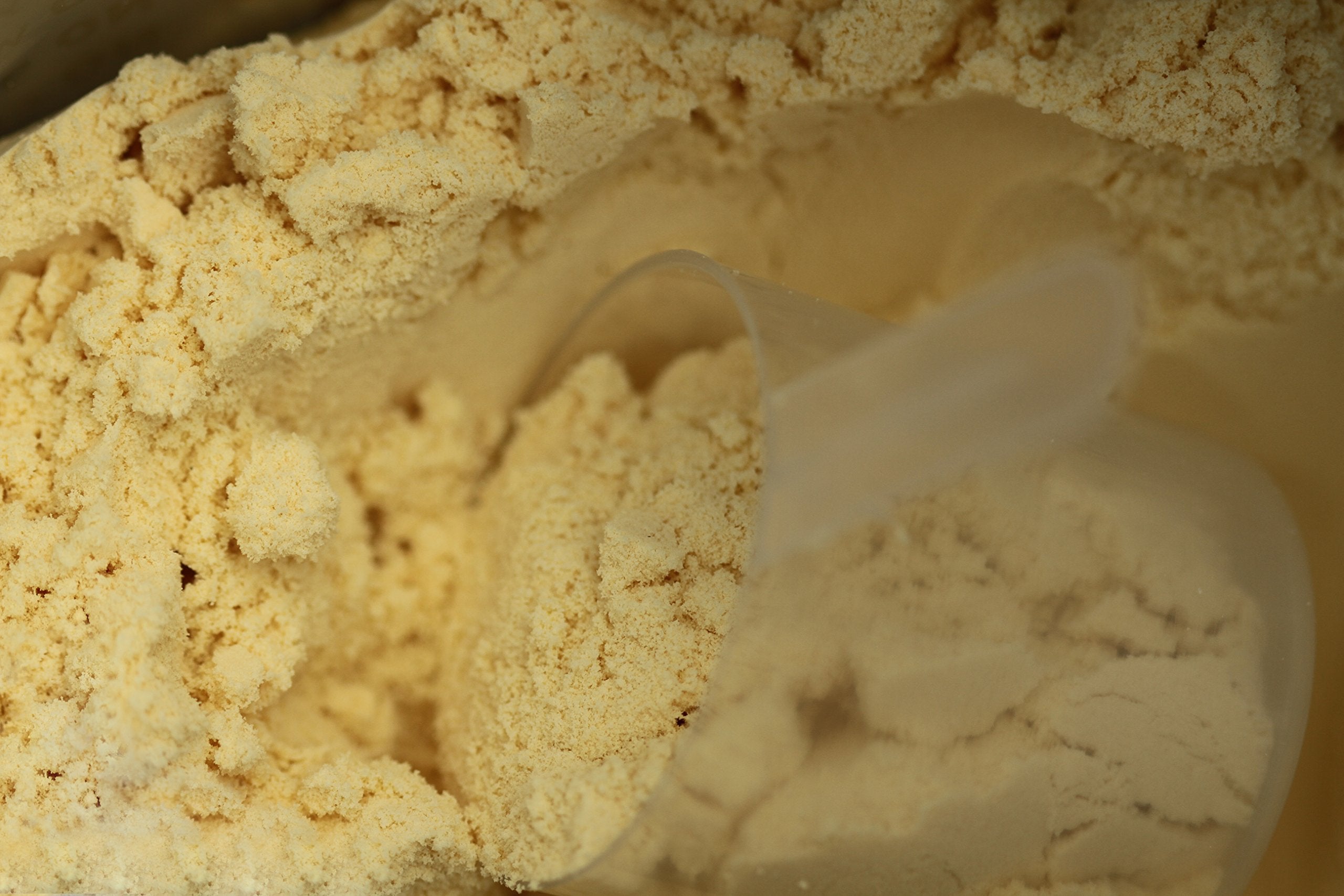 TGS Nutrition whey protein scoop beside a glass of post-workout shake