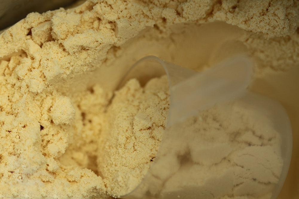 TGS Nutrition whey protein scoop beside a glass of post-workout shake