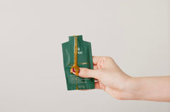 TMW Essential Longevity powder being stirred into a drink for quick daily intake.