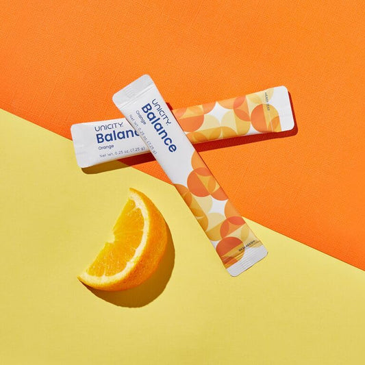 Unicity Balance Natural Orange dissolving in a glass for steady energy.