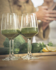 Scoop included with Mighty Maca Plus beside a vibrant green smoothie.