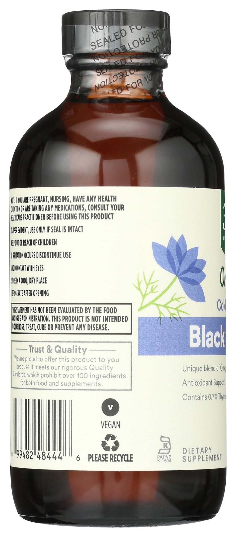 Whole Foods Market black seed oil spill on wood surface suggests culinary or wellness use
