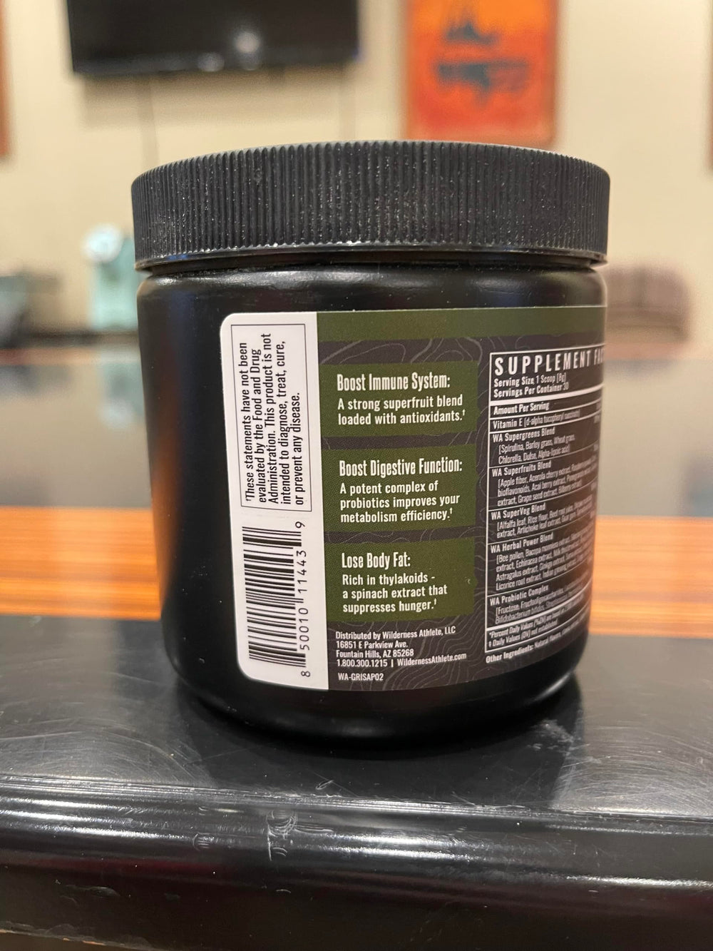 Wilderness Athlete Green Infusion powder dispense with scoop and fine texture on a bright surface.